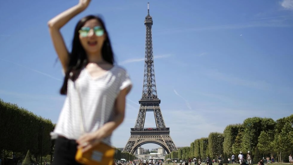 フランスのパリのエッフェル塔の前で、観光客が写真のお土産のためにポーズをとっている。© Reuters/Stephane Mahé