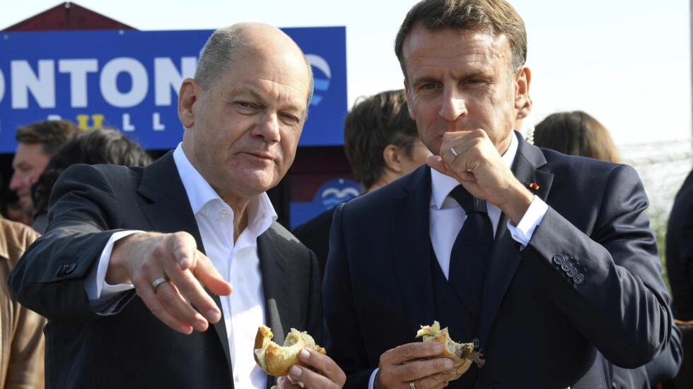 ドイツのオラフ・ショルツ首相（左）とフランスのエマニュエル・マクロン大統領は、10月火曜日にドイツのハンブルクで2日間の政府会議を締めくくるために伝統的なフィッシュロールサンドイッチを食べる。10、2023年。© ファビアン・ビマー / AP