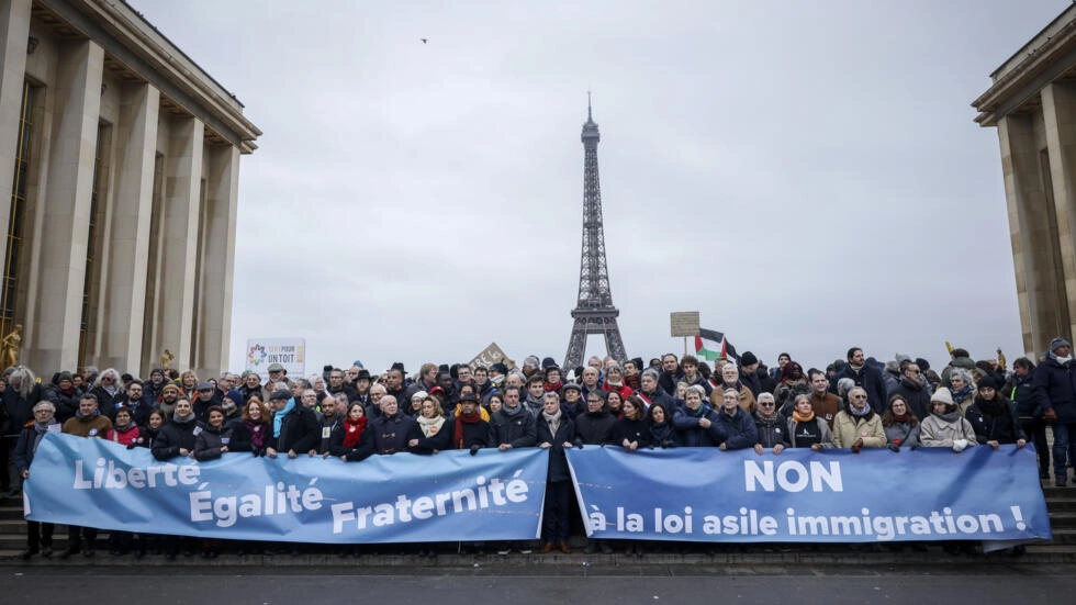フランスの移民法に反対する抗議者は、2024年1月21日、パリのエッフェル塔近くのトロカデロプラザで「自由、平等、友愛」と「移民法にノー」と書かれたバナーを掲げている。© トーマス・パディーヤ/AP