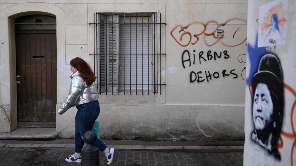 2023年11月10日、観光客に人気が高まっているマルセイユの地域、ル・パニエで「Airbnb out」を読んで落書きを歩いている女性。© AFP / ニコラス・トゥカット