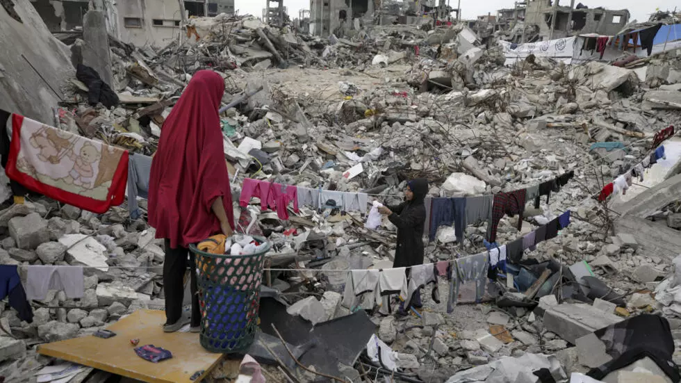 2025年2月18日、ガザ地区のジャバリヤで、イスラエル軍の地上と空の攻撃による広範囲にわたる破壊の中で、家族が彼らの財産の廃墟の中を歩いている。© ジェハド・アルシュラフィ/AP