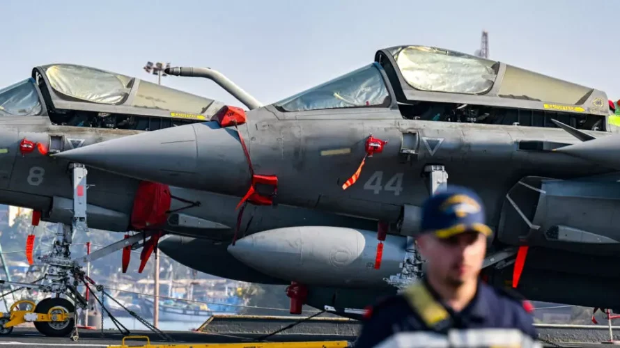 フランス海軍の要員は、パイロットのピエール・アンリ・チュエが配置された空母シャルル・ド・ゴールのメインデッキに座っているラファール戦闘機の前を歩いています。AFP - PUNIT PARANJPE