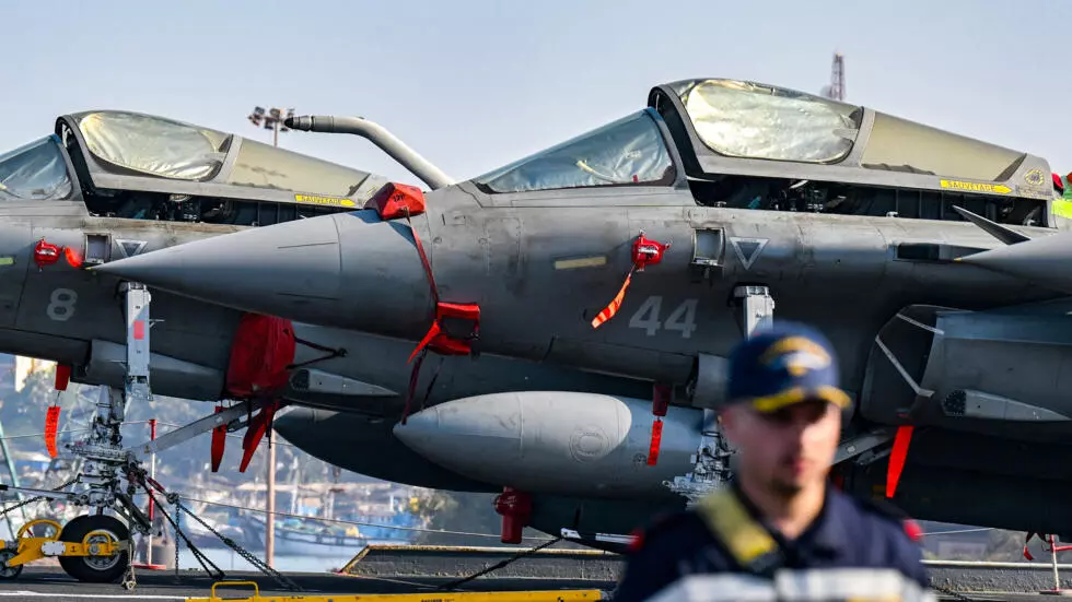 フランス海軍の要員は、パイロットのピエール・アンリ・チュエが配置された空母シャルル・ド・ゴールのメインデッキに座っているラファール戦闘機の前を歩いています。AFP - PUNIT PARANJPE